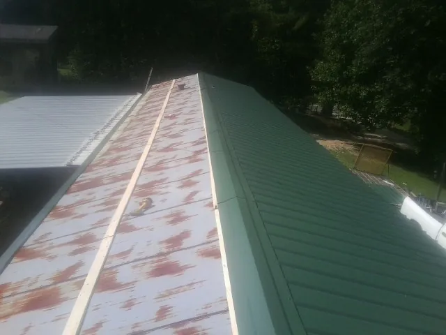 Old rusted panels beside newly installed green metal roofing — Wind Damage Roof Repair by Roofing Brothers in Olmsted Falls