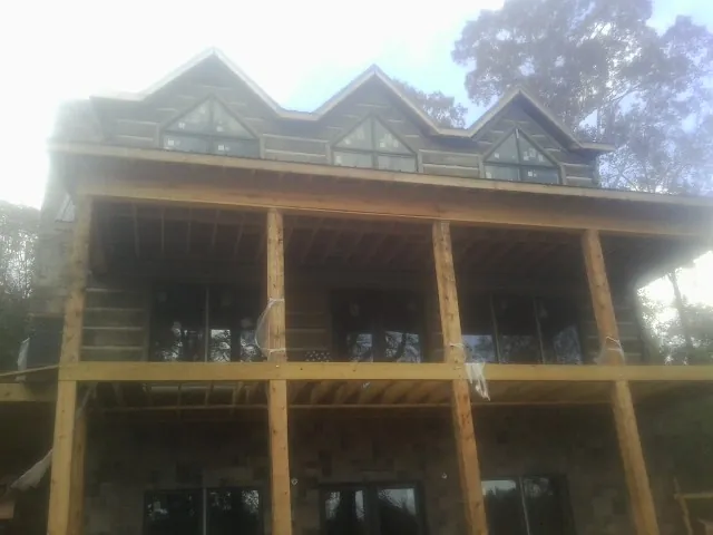 Dormers and porch framing on a large log home under construction — Roof Coating work by our crew in Olmsted Falls