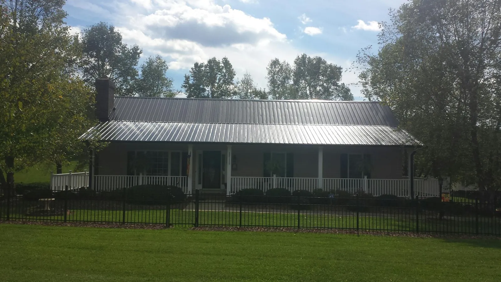 Gray metal roof on a brick ranch with a full width front porch — Gutter Guard Installation work by our crew in Olmsted Falls