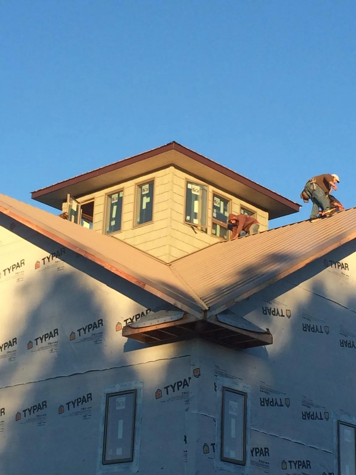 Roofers working around a rooftop cupola on a new metal roof at sunset — Roof Waterproofing in Olmsted Falls by Roofing Brothers
